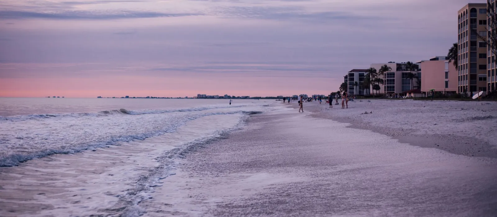 A pink sunset sky over a Gulf coast beach