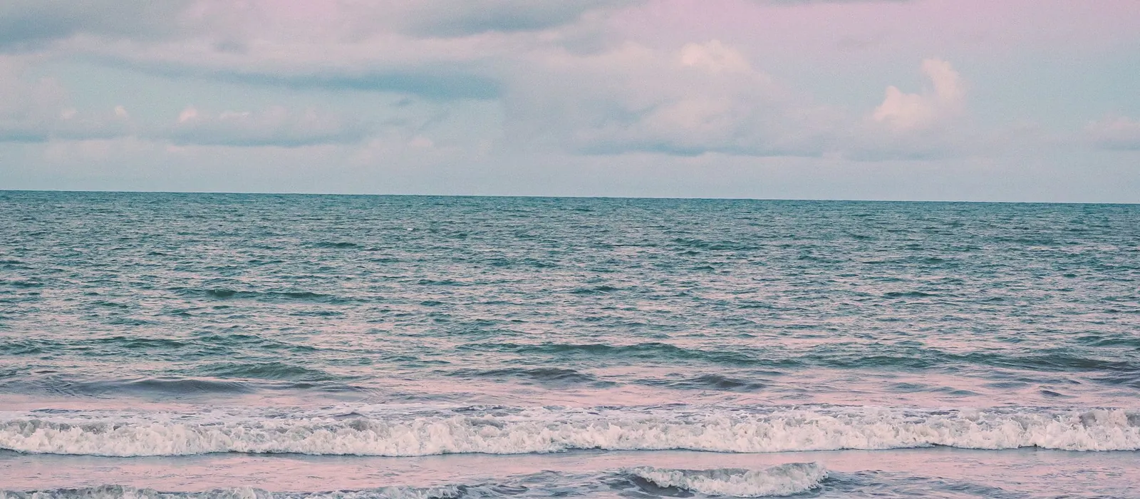 Calm turquoise water under a soft pink sky