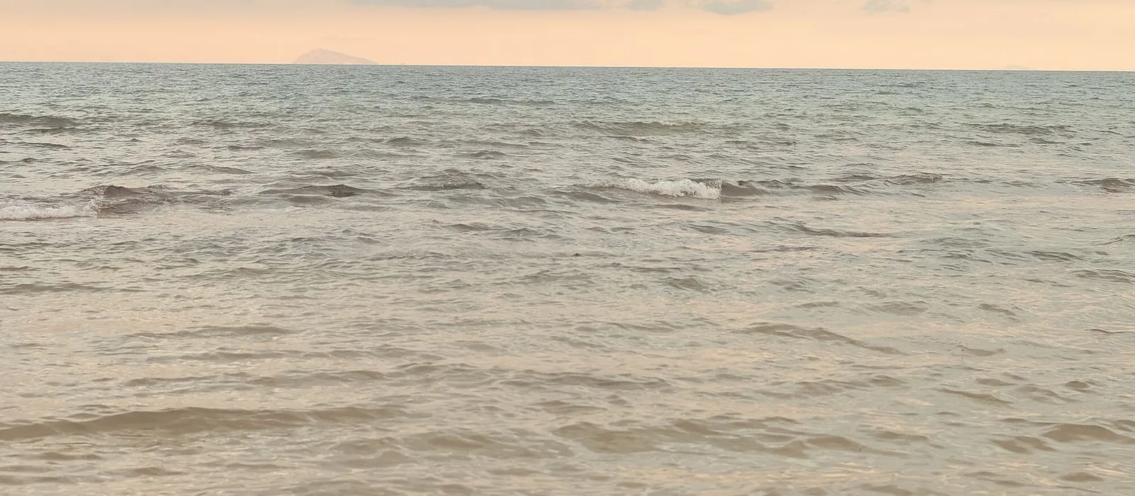 Gentle surf on a wide, quiet beach at dusk