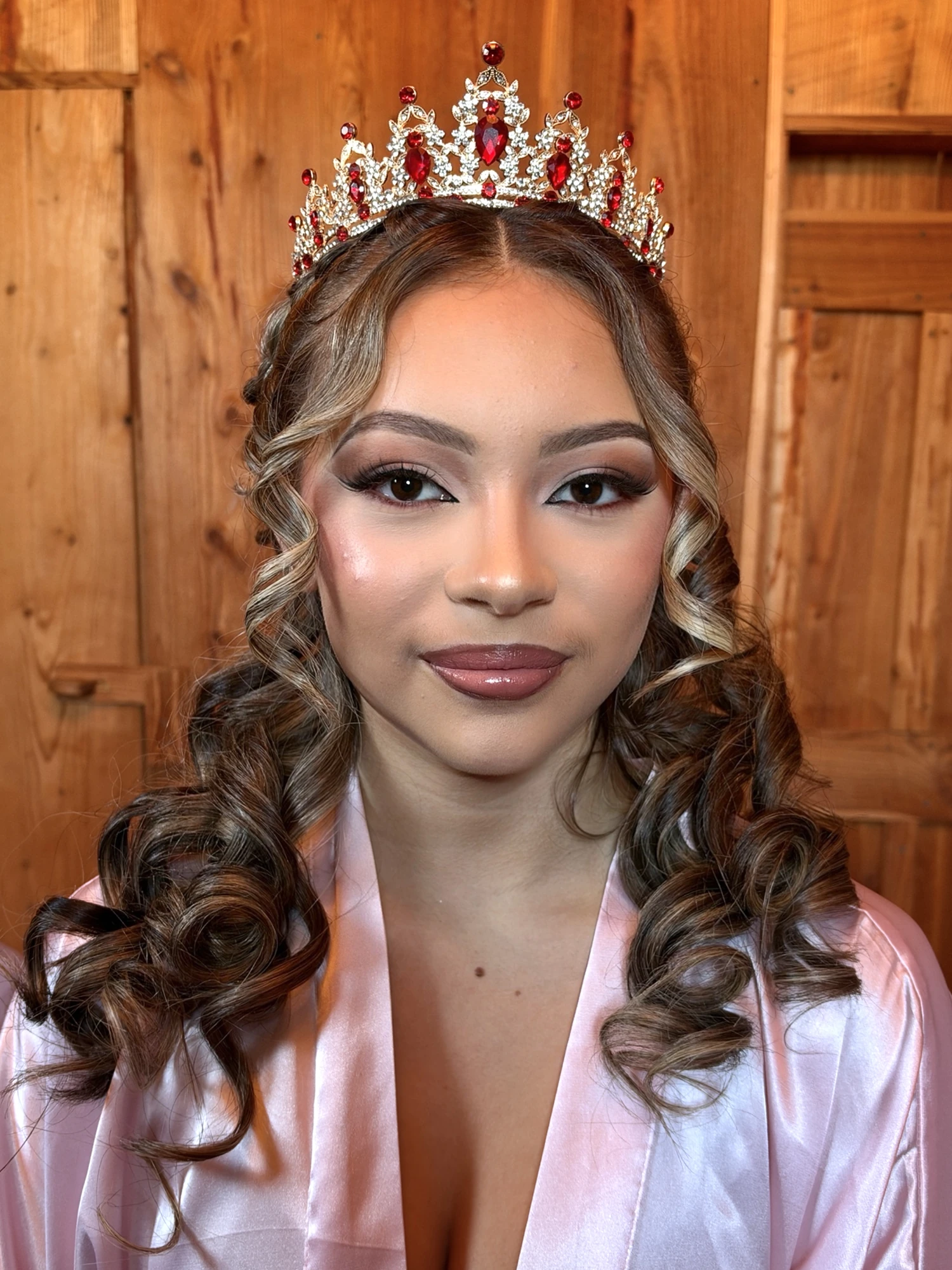 Quinceanera makeup with a rhinestone tiara and long spiral curls, front facing