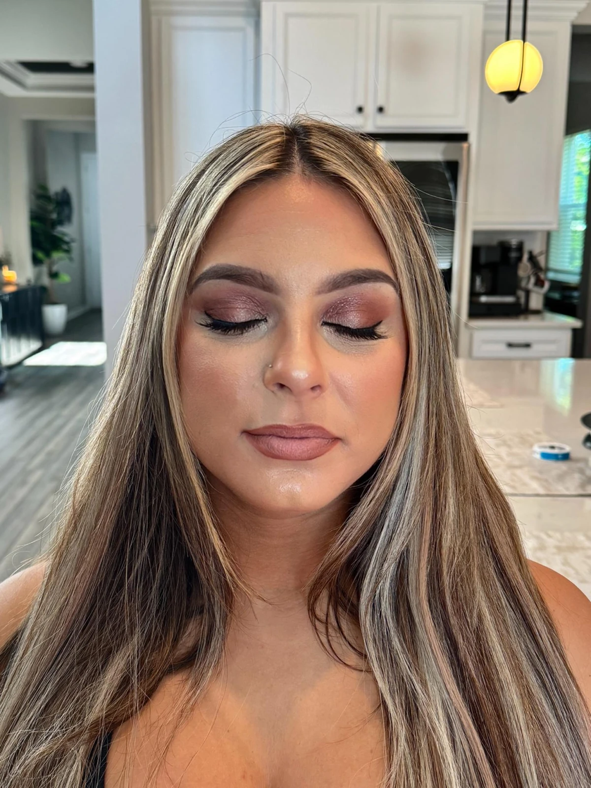 Soft glam makeup with a plum smoky eye, eyes closed